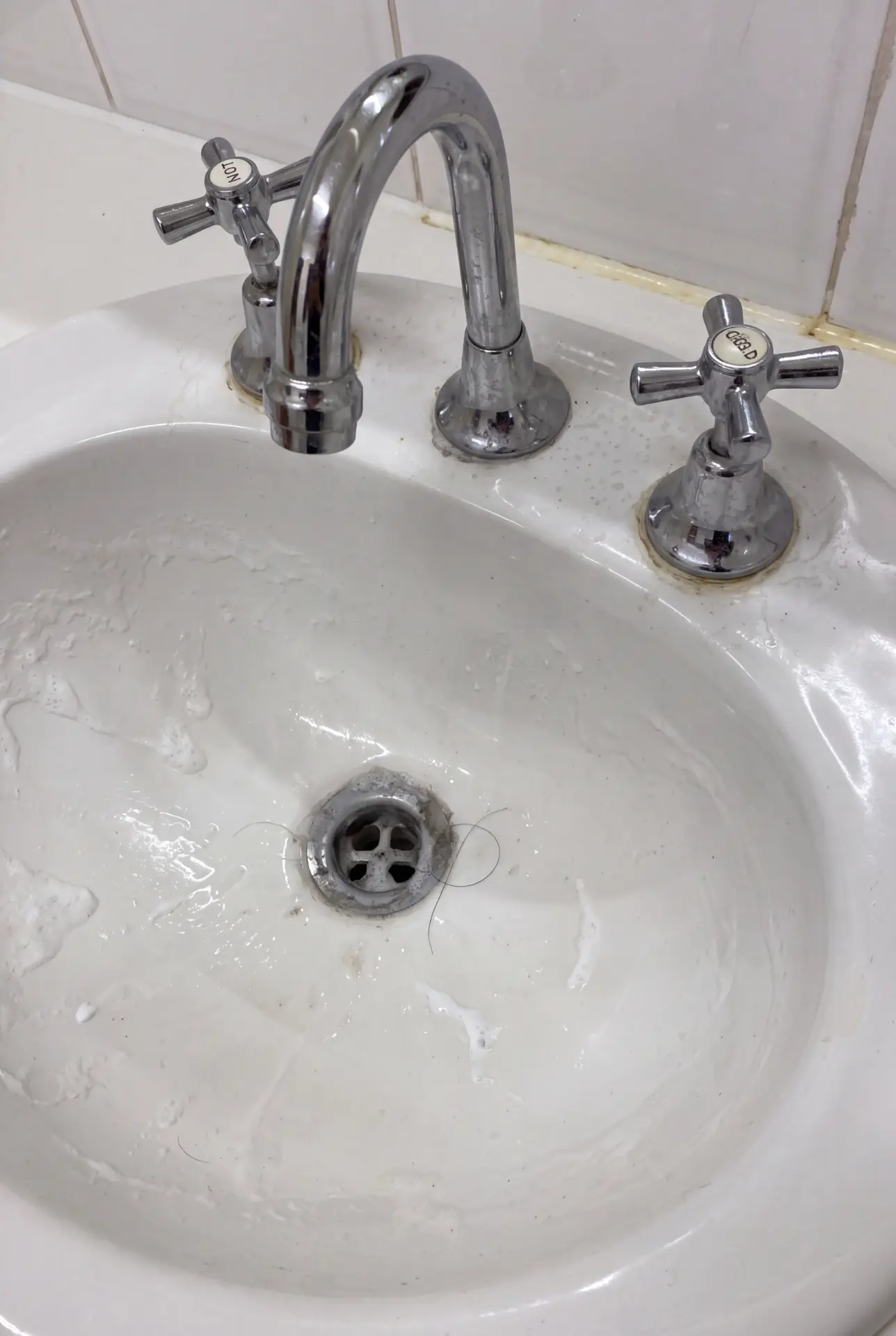 Dirty bathroom basin and taps before cleaning